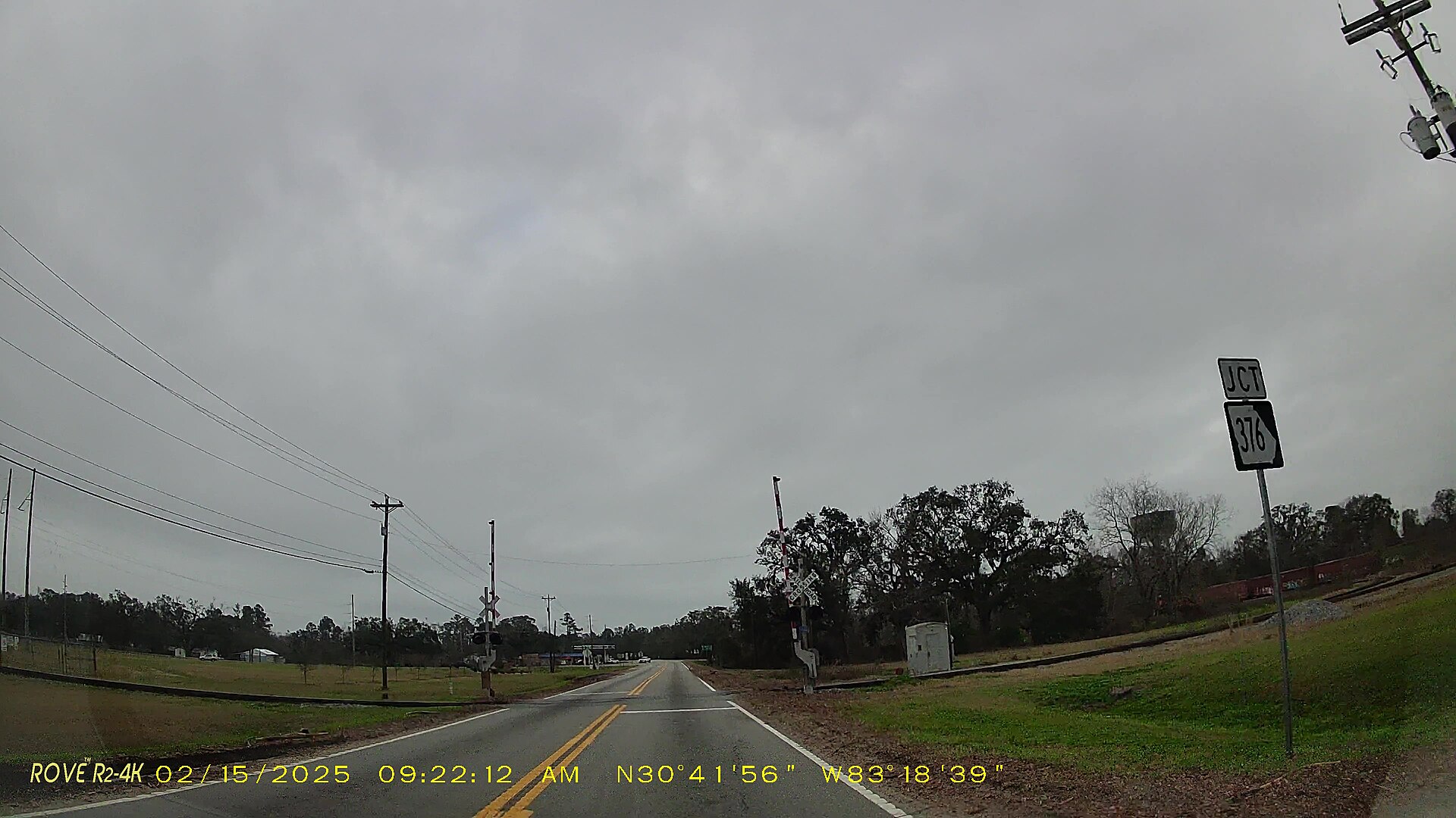 Dashcam view of a quiet road junction under a grey sky